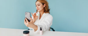 Direct sales consultant demonstrating innovative product marketing strategies by taking a selfie with skincare products, emphasizing the versatility and customer engagement.