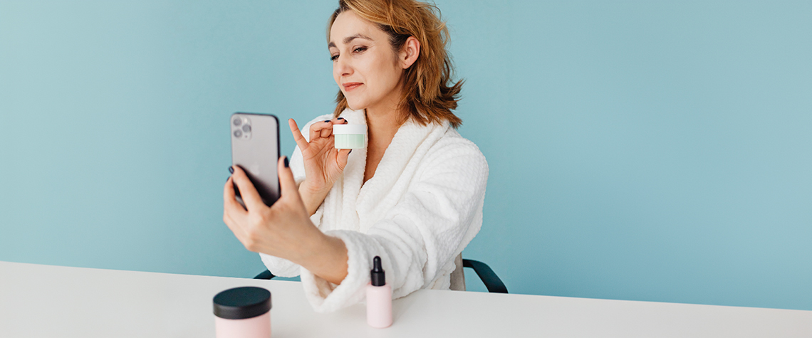 Direct sales consultant demonstrating innovative product marketing strategies by taking a selfie with skincare products, emphasizing the versatility and customer engagement.