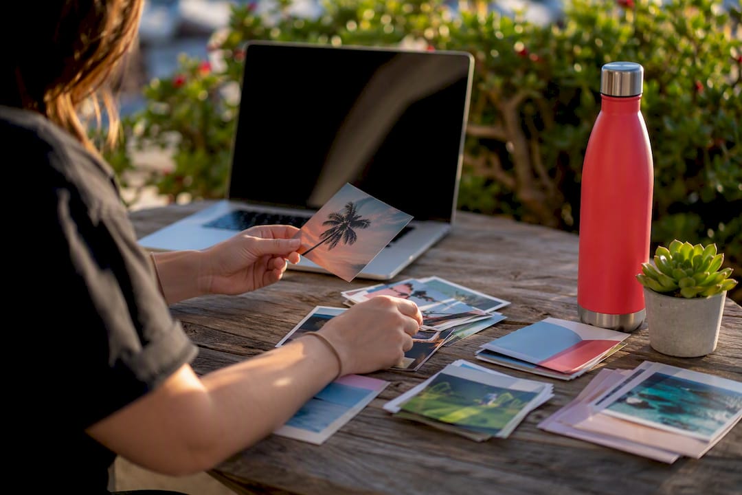 Hands browsing physical media cards by laptop